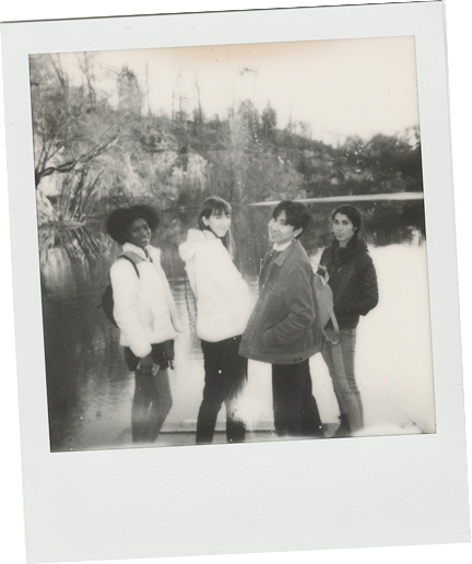 Black and white polaroid of Claire and friends by a lake.